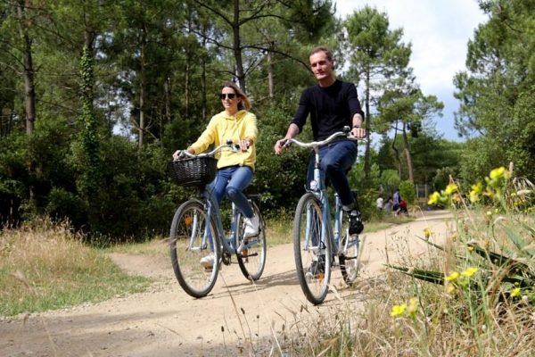 couple cycling on a forest path in pays de saint jean de monts