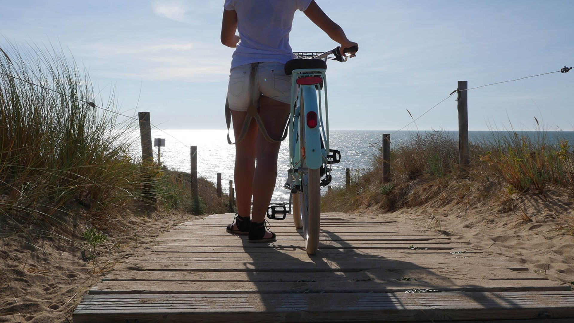 woman walking to the beach with its bike