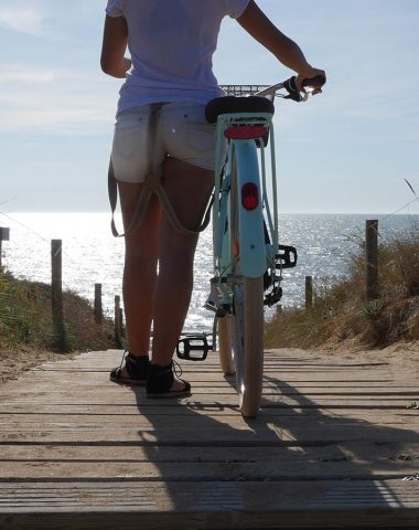 woman walking to the beach with its bike