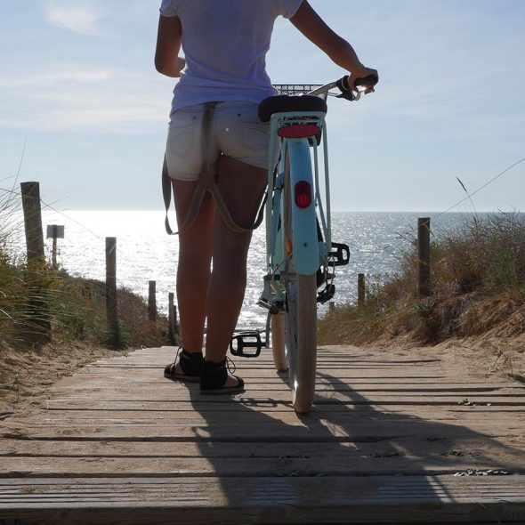 woman walking to the beach with its bike