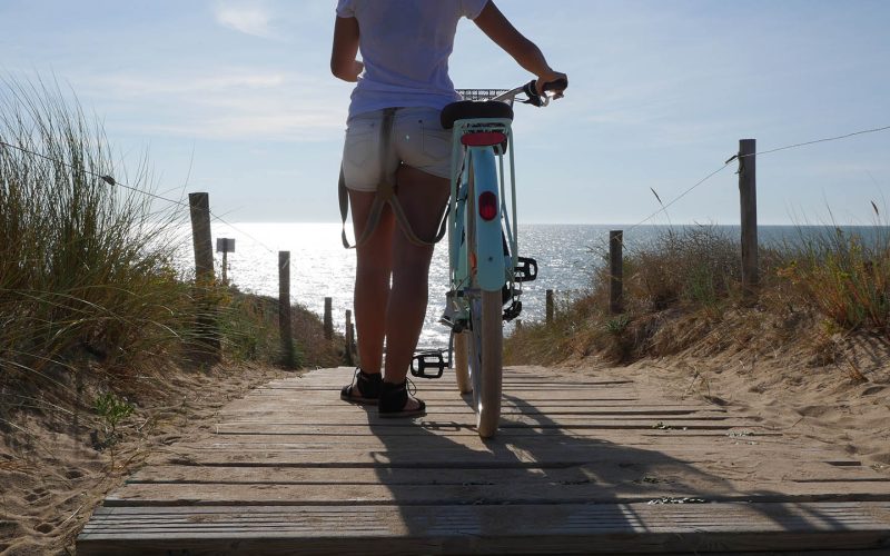 woman walking to the beach with its bike