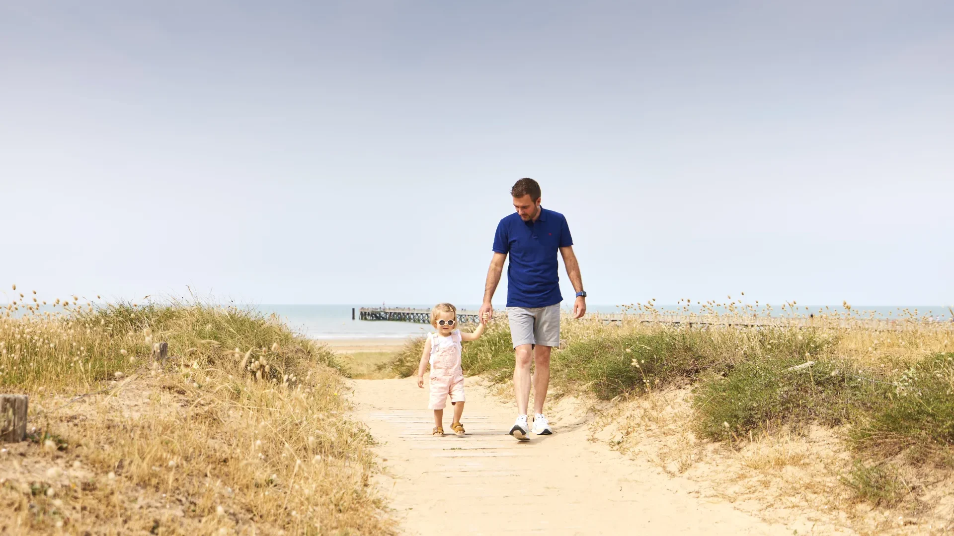 Picture of a father and his daughter walking in the sand in pays de saint jean de monts, in Vendée, France