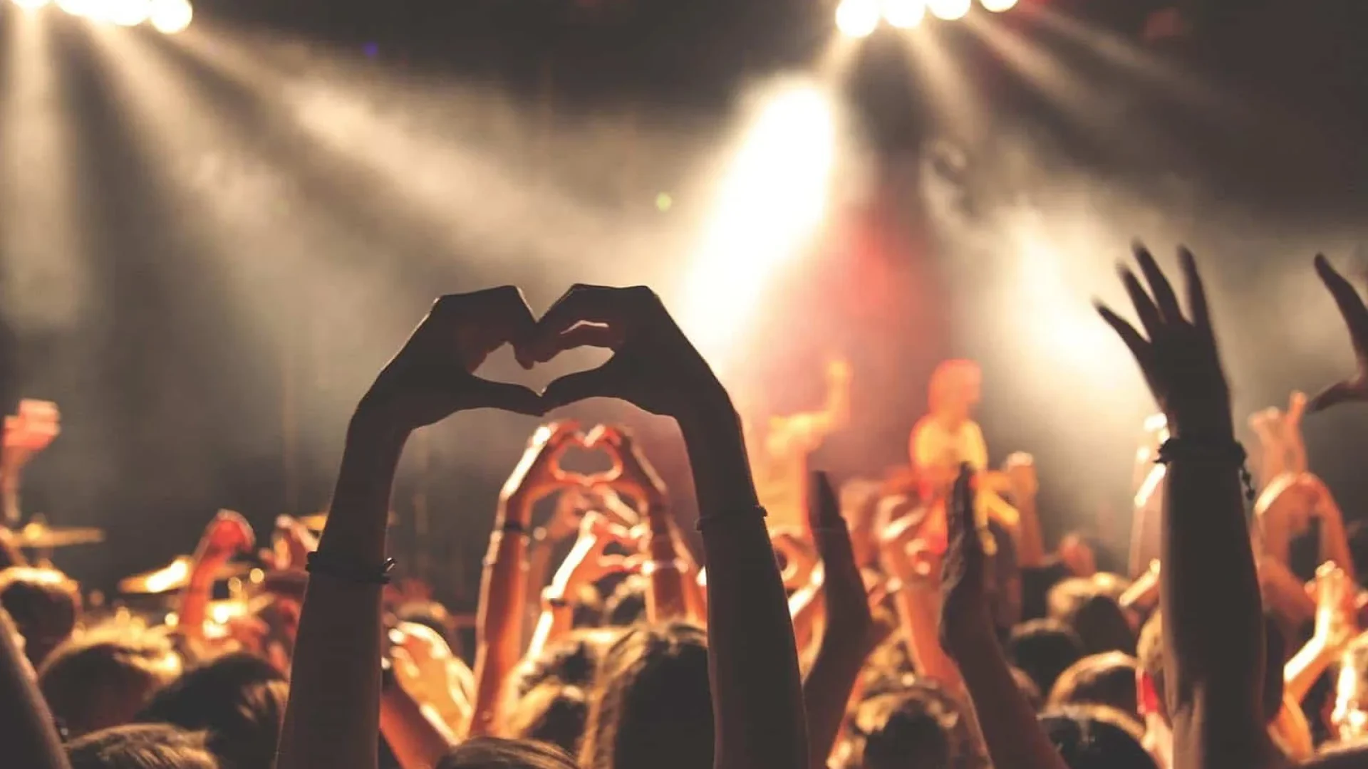 Photo showing people attending a show and forming a heart with their hands
