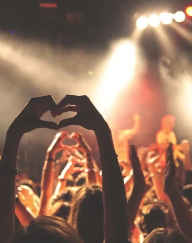 Photo showing people attending a show and forming a heart with their hands
